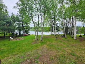 A serene lakeside setting with birch trees, a grassy area, and a dock with boats. - Bayview  1 (Mercer)