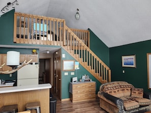 A cozy living space with a wooden staircase, a kitchen area, and a comfortable seating area. - Bayview  1 (Mercer)