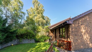 A brick building with a wooden deck and a stone wall. - Glenfiddich by Interhome (Aviemore)