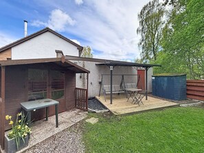 Une maison avec un patio, une balançoire et un petit jardin.