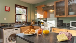 A modern kitchen with a built-in washer, a microwave, and a stove. - Glenfiddich by Interhome (Aviemore)