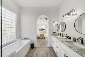A modern bathroom with a large bathtub, two sinks, and a vanity with a mirror. - Lakefront Oasis (Glendale)