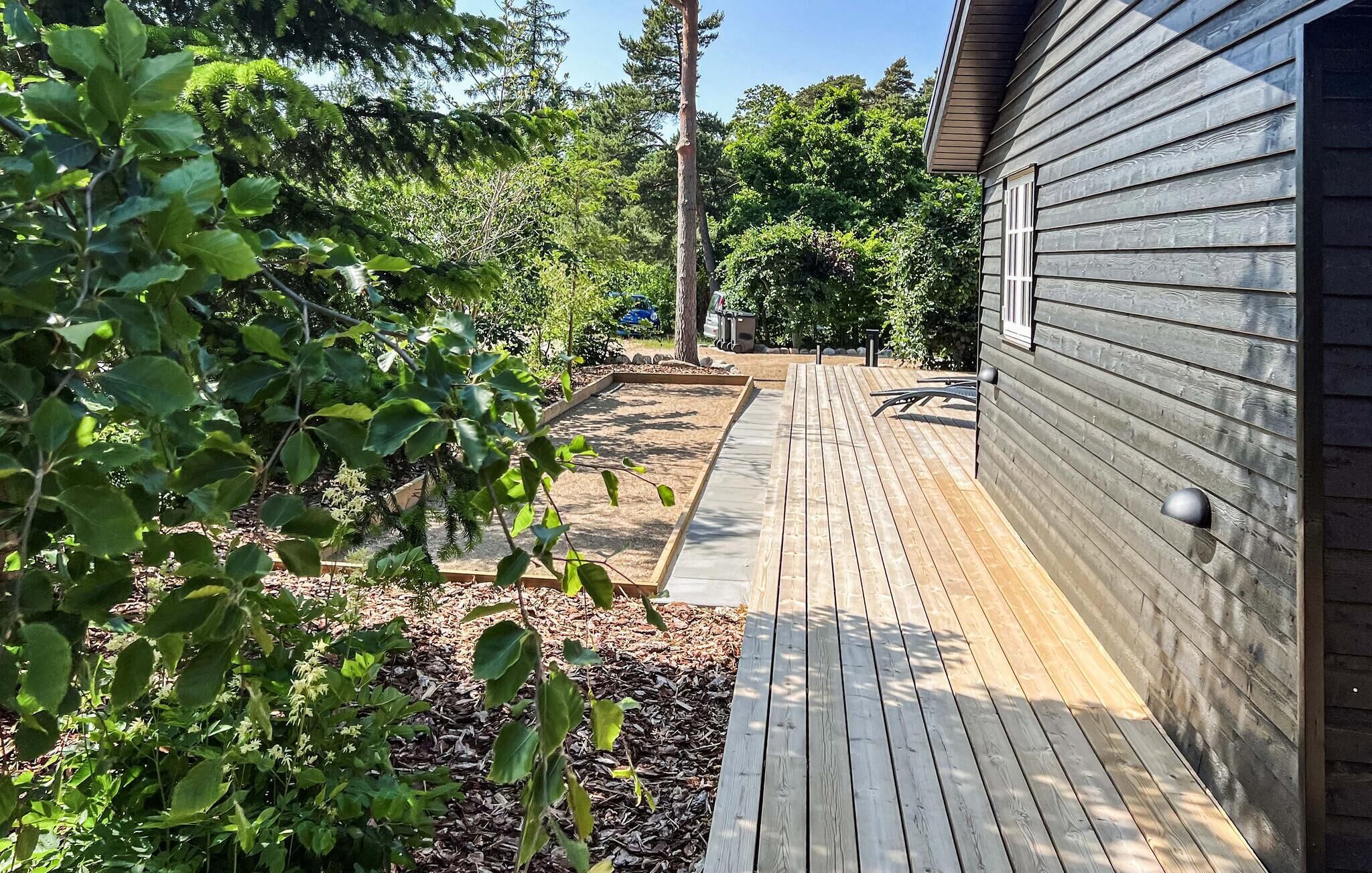 A wooden deck adjacent to a house with a metal railing.
