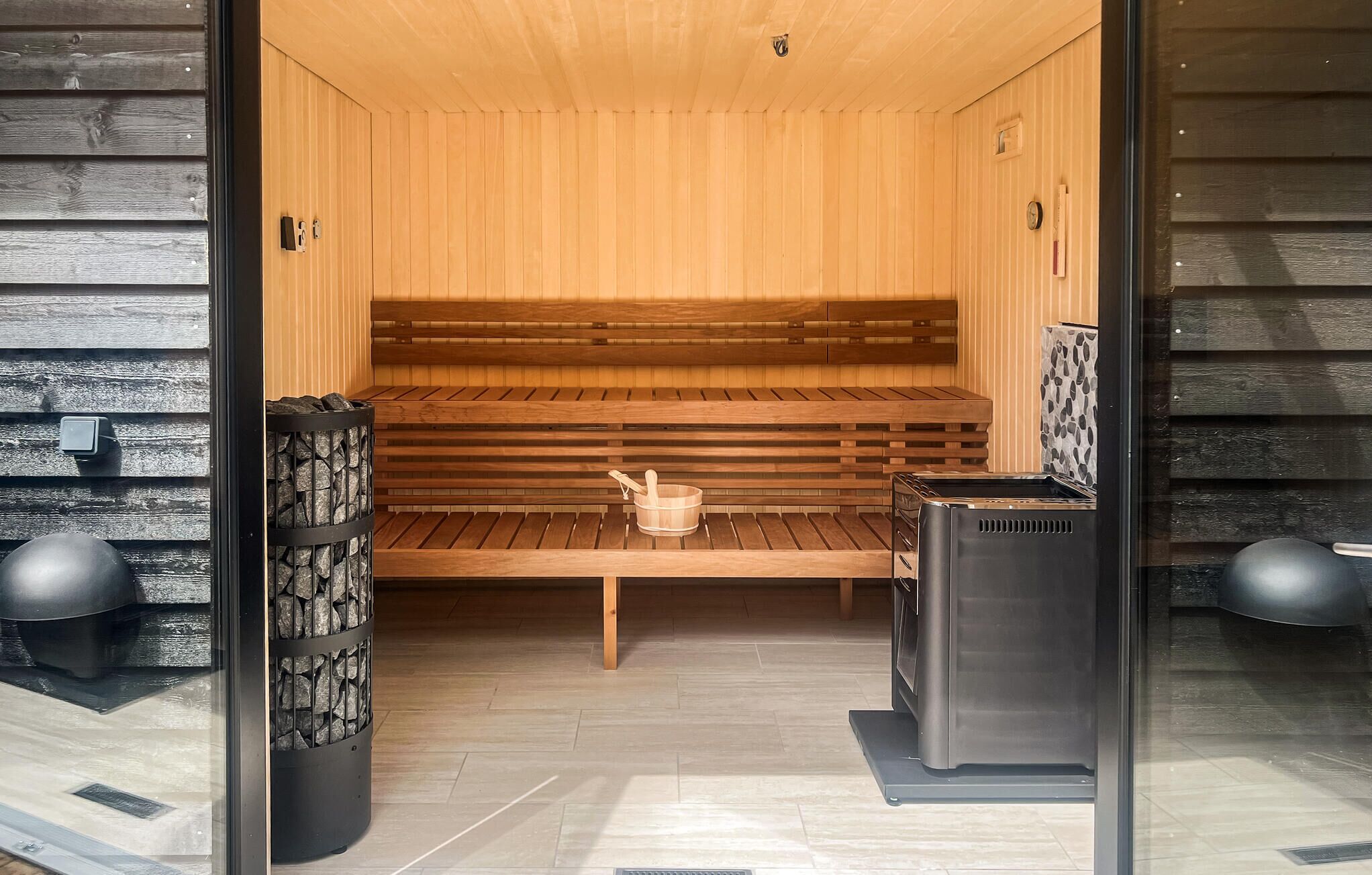 Un sauna avec des bancs en bois, un poêle en pierre et un appareil de sauna.