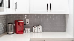A kitchen with white cabinets, a coffee maker, a kettle, and two containers on the counter. - Papago Polka (Scottsdale)