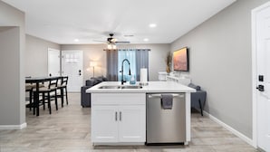 A modern kitchen with a central island, white cabinetry, and a stainless steel dishwasher. - Papago Polka (Scottsdale)