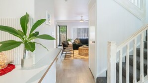 Un pasillo con una escalera, un comedor con una mesa y sillas, y una sala de estar con un sofá y una mesita de centro.