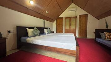 Quarto com uma cama grande, uma cama menor, armários de madeira e um tapete vermelho.
