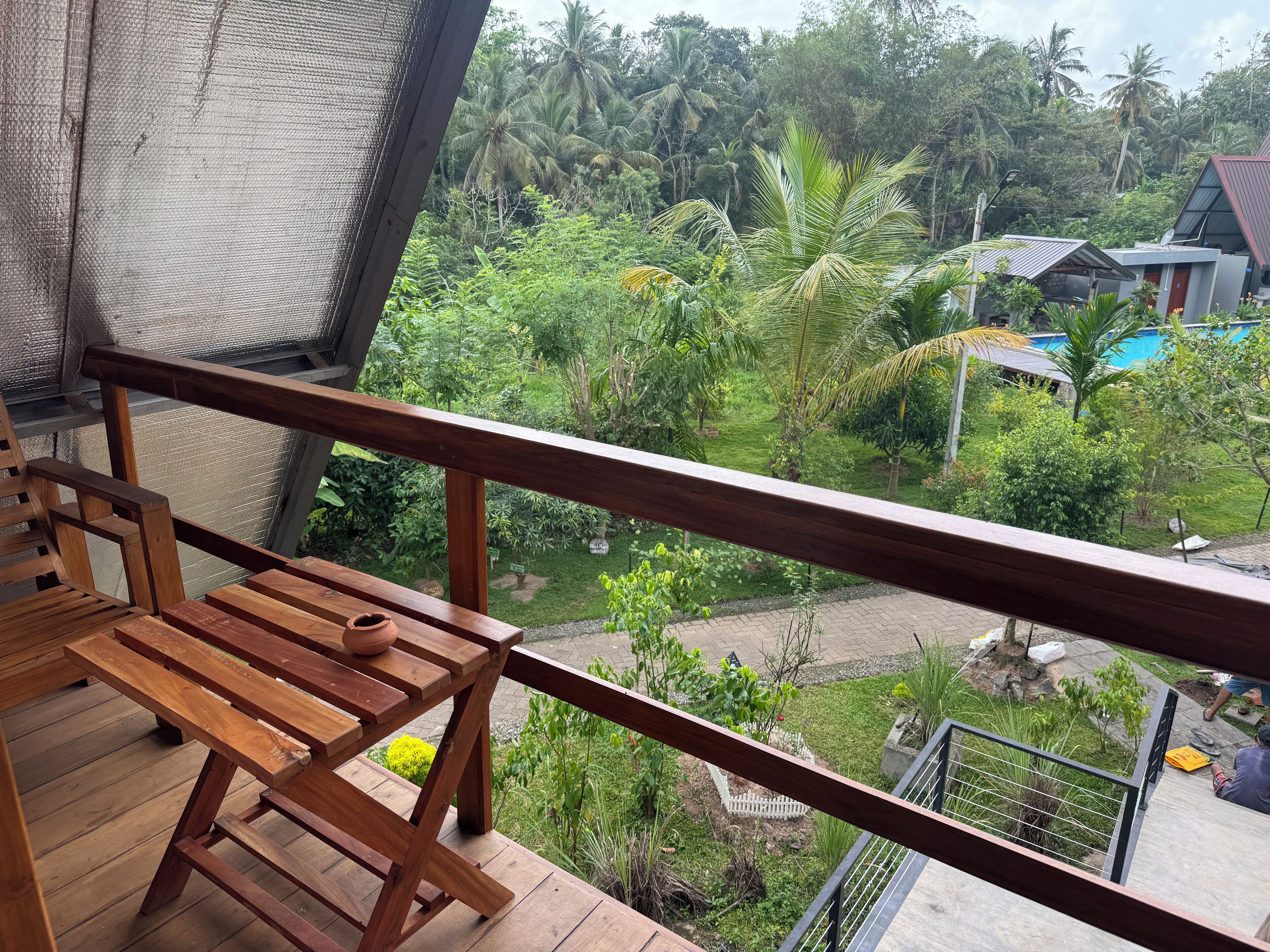 A wooden deck with a view of a lush garden and a swimming pool.