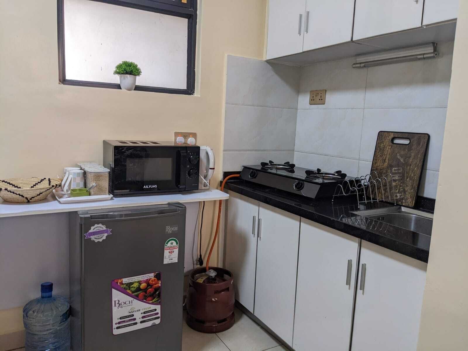 A compact kitchen with a Bosch refrigerator, a microwave, a gas stove, and a sink.