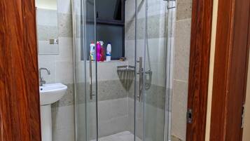 Une salle de bain moderne dotée d’une douche à parois de verre, d’un lavabo et de toilettes.