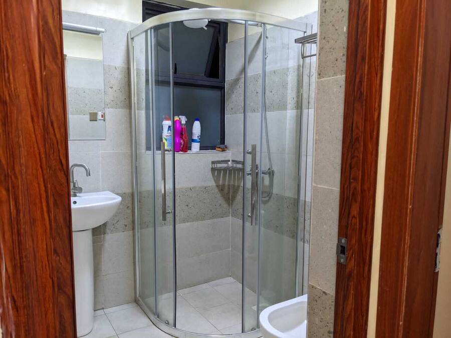 Une salle de bain moderne dotée d’une douche à parois de verre, d’un lavabo et de toilettes.