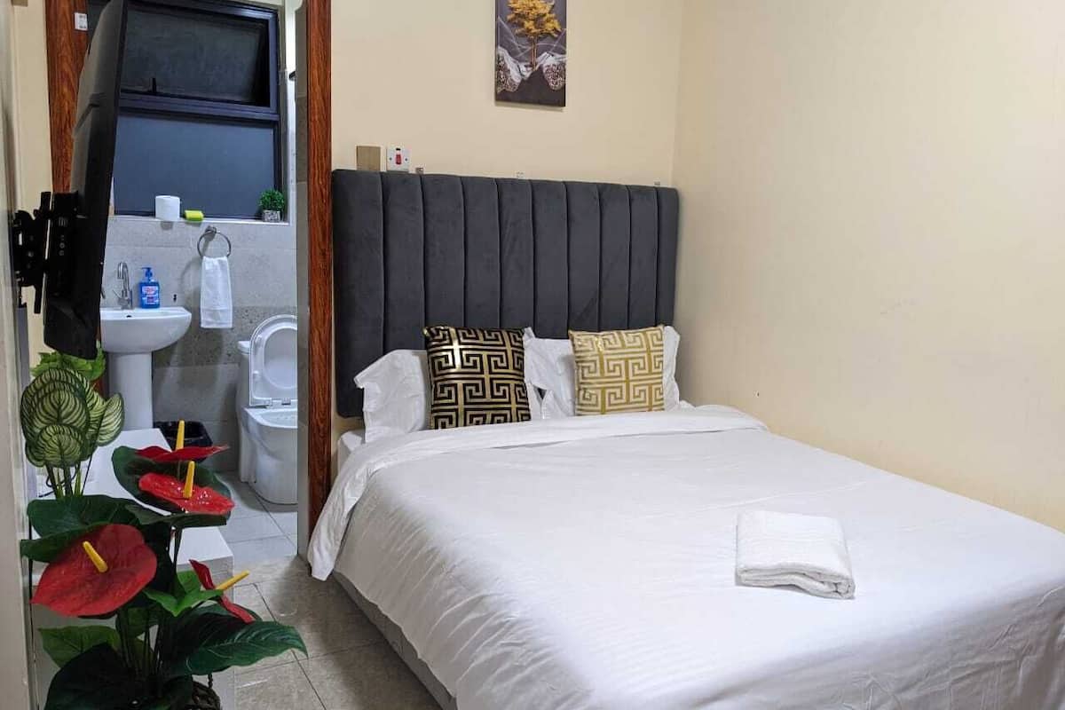 Una habitación de hotel con cama, ventana, lavamanos y retrete.