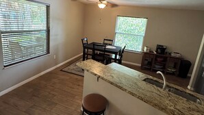 A kitchen with a bar area, wooden flooring, and a ceiling fan. - Hidden Spring-run• Swimming • elevated Views & Game Rm (Spring Hill)