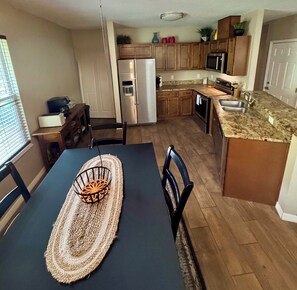 A compact kitchen with a dining area, wooden cabinets, a refrigerator, and a microwave. - Quiet getaway on a hidden Spring-run (Spring Hill)