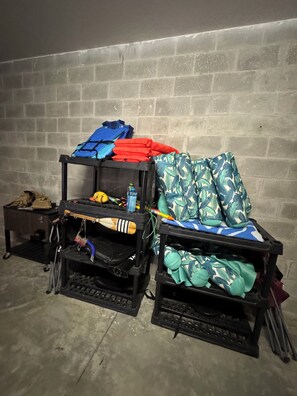 Two black storage units with various items, including folded clothes and a water bottle, against a brick wall. - Hidden Spring Run • Elevated Views • 2 Kings • 75" Smart TV • kayaks • Game Rm (Spring Hill)