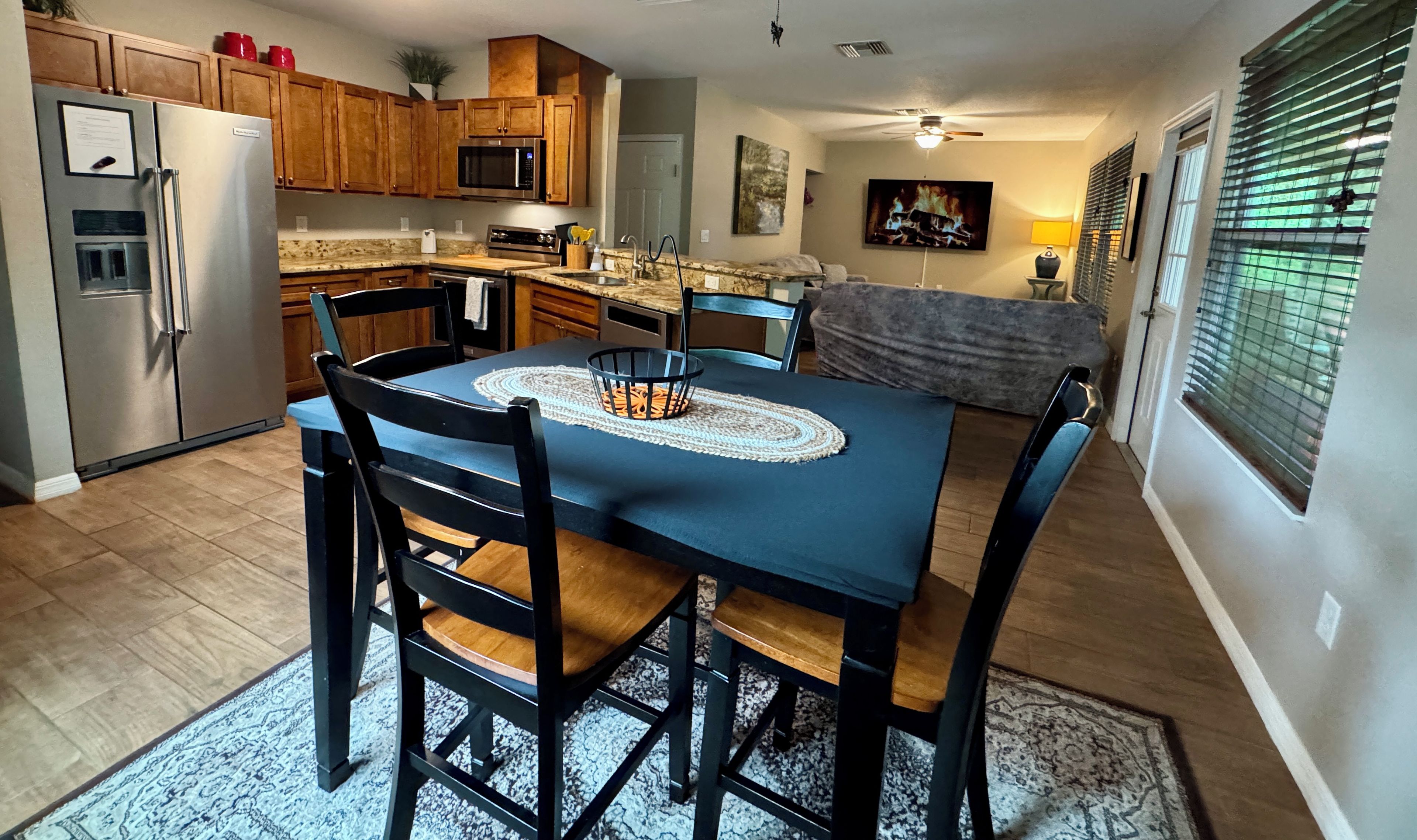 A kitchen with a dining table, chairs, and a refrigerator.