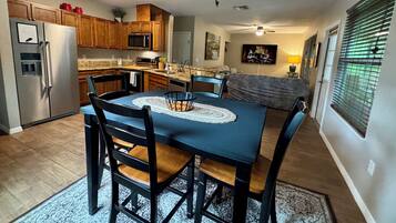 A kitchen with a dining table, chairs, and a refrigerator.