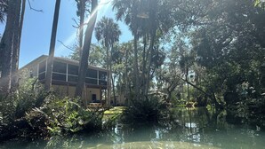 A building surrounded by dense trees and a calm water body. - Hidden Spring-run• Swimming • elevated Views & Game Rm (Spring Hill)