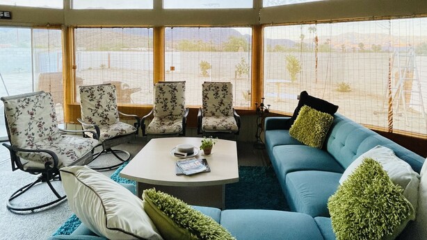 Une pièce avec un canapé bleu, des fauteuils à motifs floraux, une table basse et un lustre.