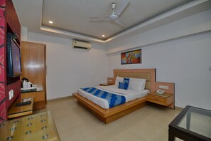 Une chambre d’hôtel moderne avec un grand lit, des tables de chevet, un ventilateur de plafond, un appareil de climatisation et un tableau au mur.