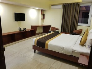 Une chambre d’hôtel avec un grand lit, un bureau, une chaise, une télévision et un appareil de climatisation.