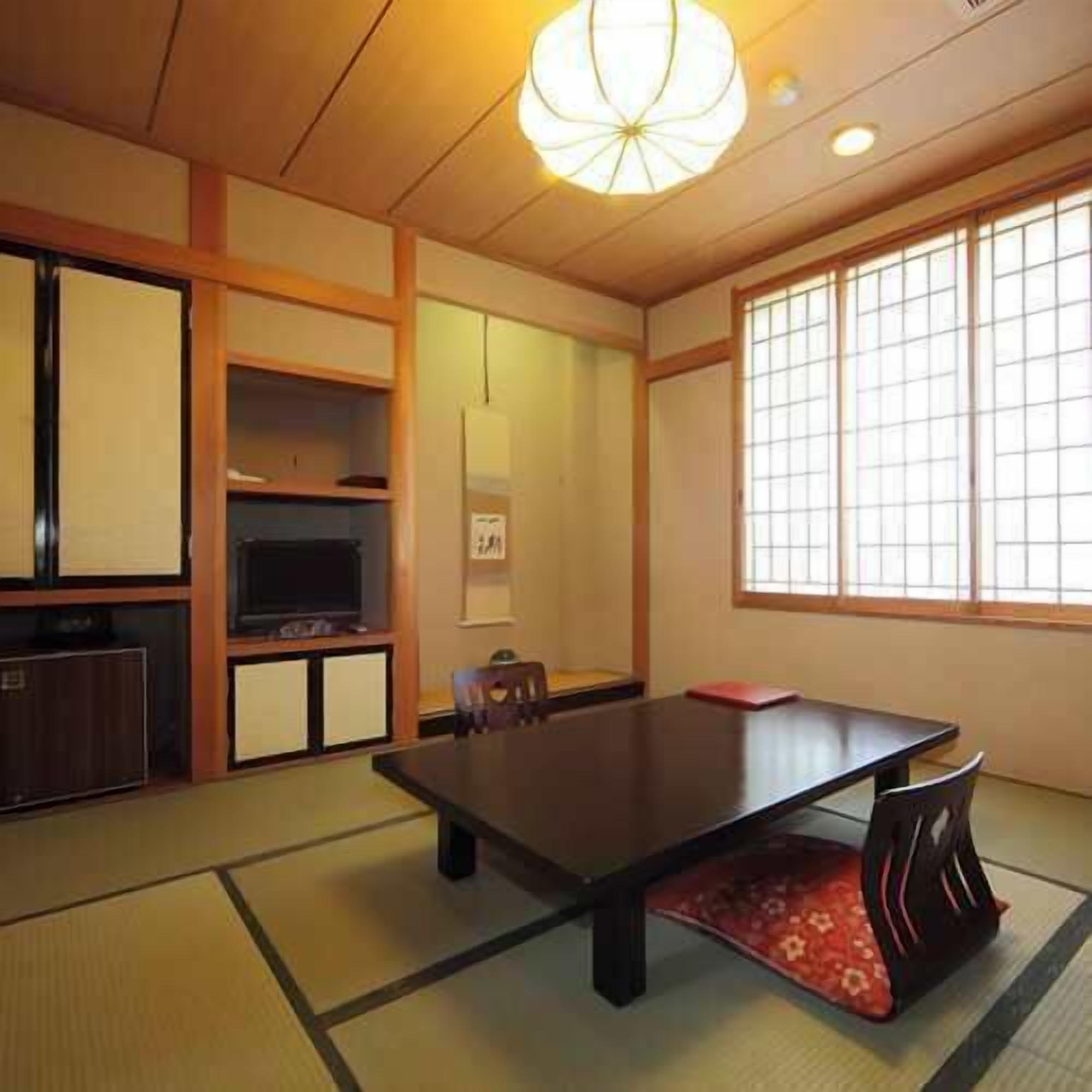 A traditional Japanese room with tatami flooring, a low table, and sliding doors.