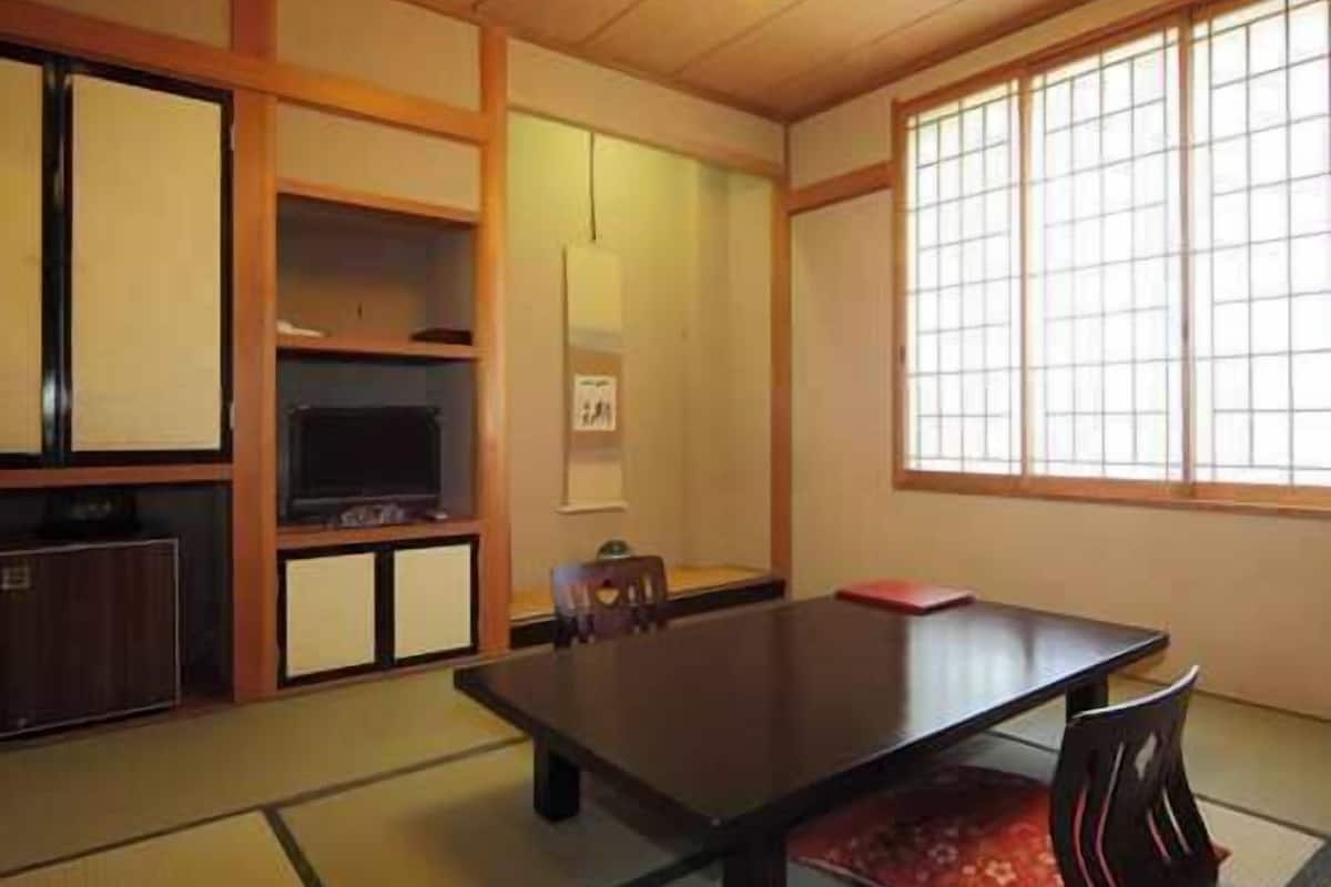 A traditional Japanese room with tatami flooring, a low table, and sliding doors.