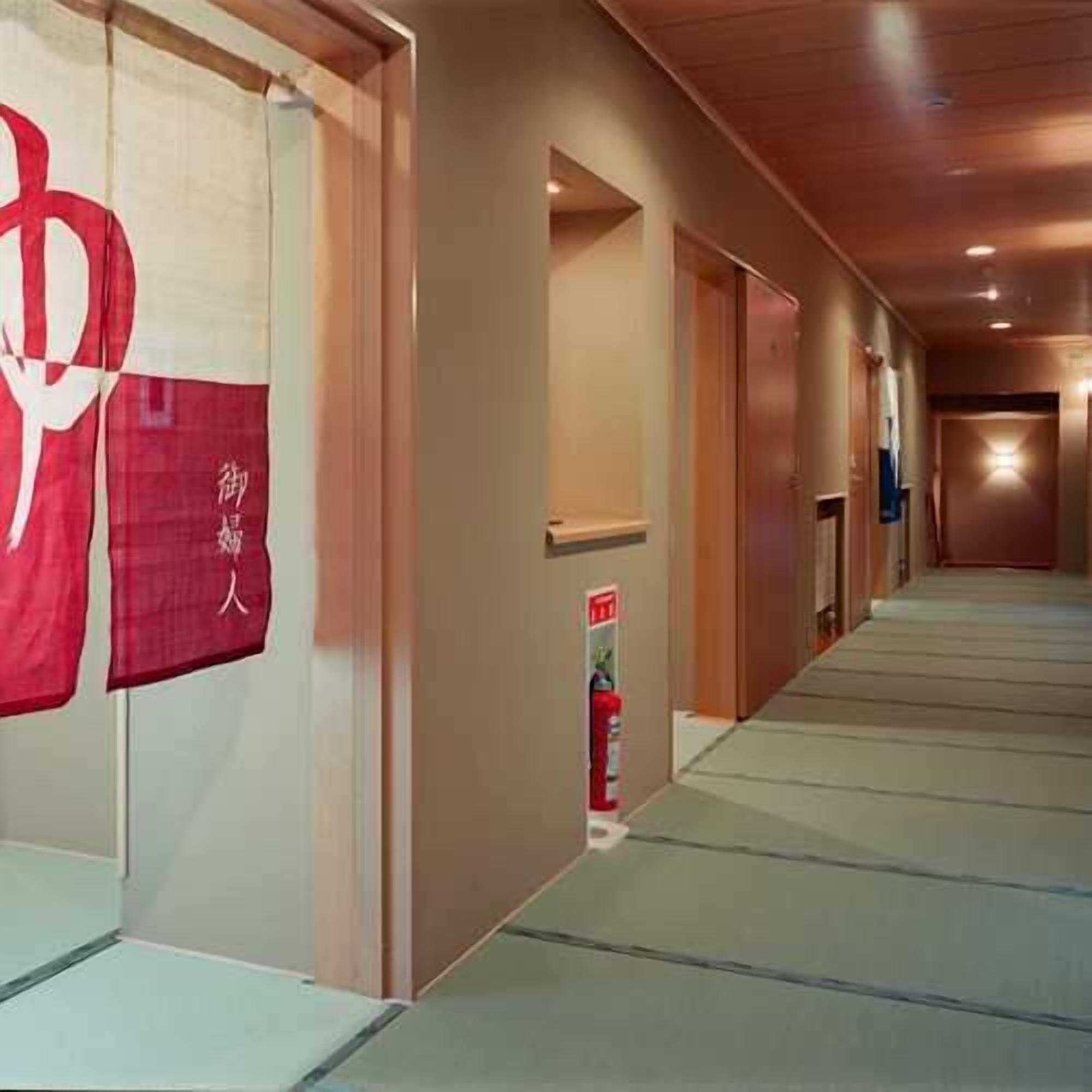 A hallway with a fire extinguisher, a door, and a wall with a red and white sign.