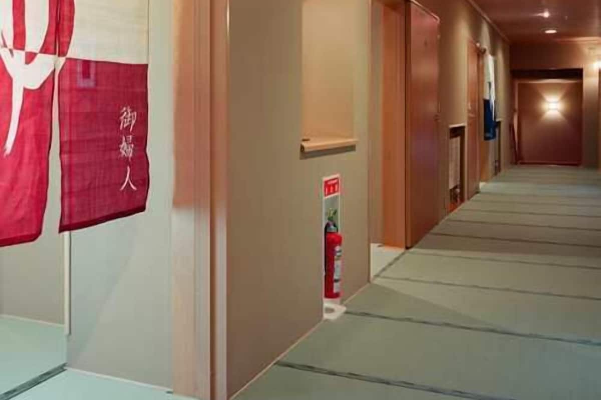 A hallway with a fire extinguisher, a door, and a wall with a red and white sign.