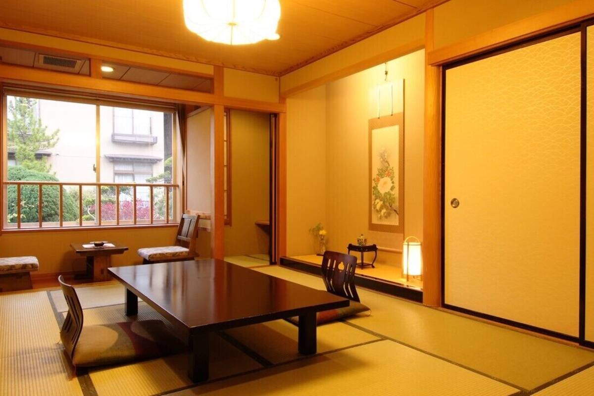 A traditional Japanese room with tatami flooring, a low table, chairs, and sliding doors.