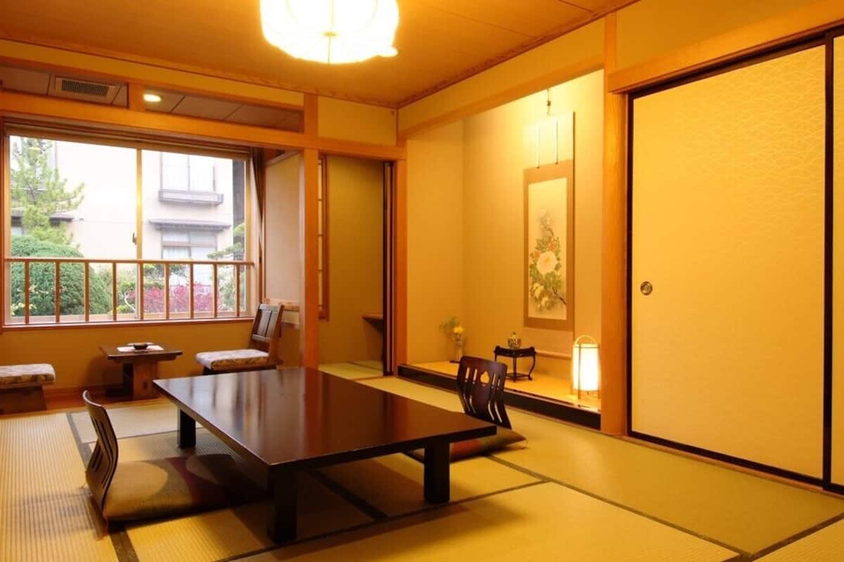 A traditional Japanese room with tatami flooring, a low table, chairs, and sliding doors.