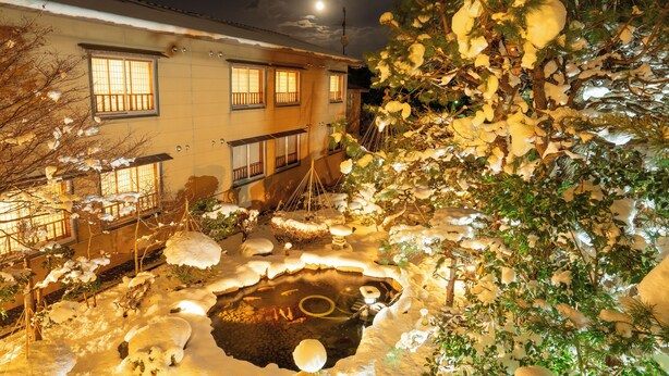 Un bâtiment de style japonais traditionnel, doté d’un jardin enneigé et d’un étang.