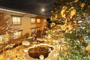 Un edificio tradicional japonés con un jardín nevado y un estanque.
