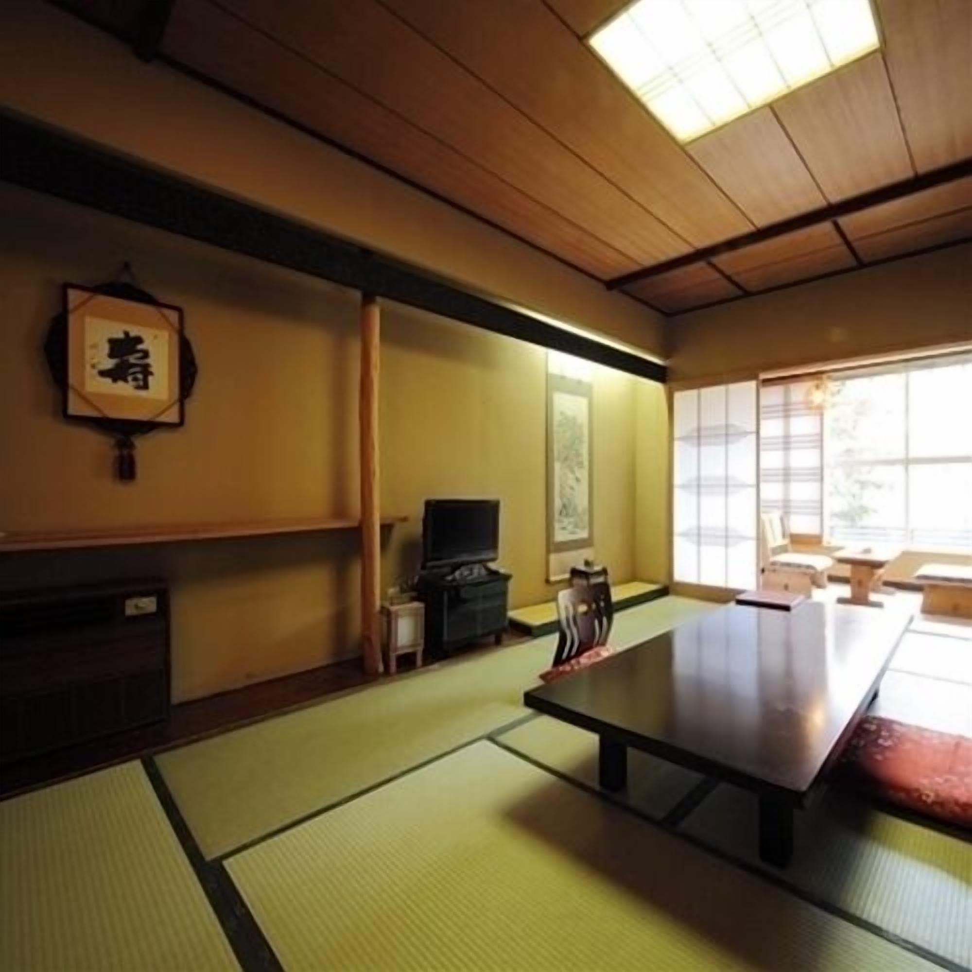 A traditional Japanese room with tatami flooring, a low table, a television, and a sliding door.
