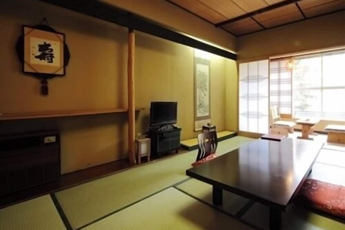 A traditional Japanese room with tatami flooring, a low table, a television, and a sliding door.