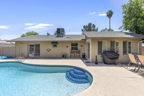 A residential backyard with a swimming pool, a covered grill, and outdoor seating. - Vista Villa (Scottsdale)