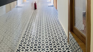 A long, narrow hallway with patterned flooring, recessed lighting, and wooden doors on one side. - CABIN STAY AIRPORT-THE HUBZ (Mumbai)