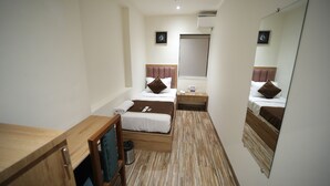 A hotel room with two beds, a wooden desk, a TV, a ceiling fan, and a large mirror. - CABIN STAY AIRPORT-THE HUBZ (Mumbai)