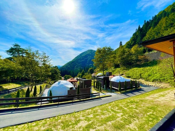 A modern outdoor area with a paved walkway, two dome-shaped structures, and a wooden fence. - GRAN CLASSE (Shimonita)