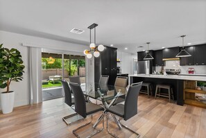 Una cucina moderna con mobili neri, un tavolo da pranzo in vetro e un'ampia finestra con vista su un giardino.