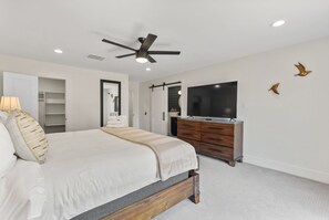 Una camera da letto con un letto, una cassettiera, una televisione e una ventola a soffitto.