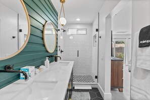 Un bagno moderno con due lavabi, una doccia e un mobile vanitario.