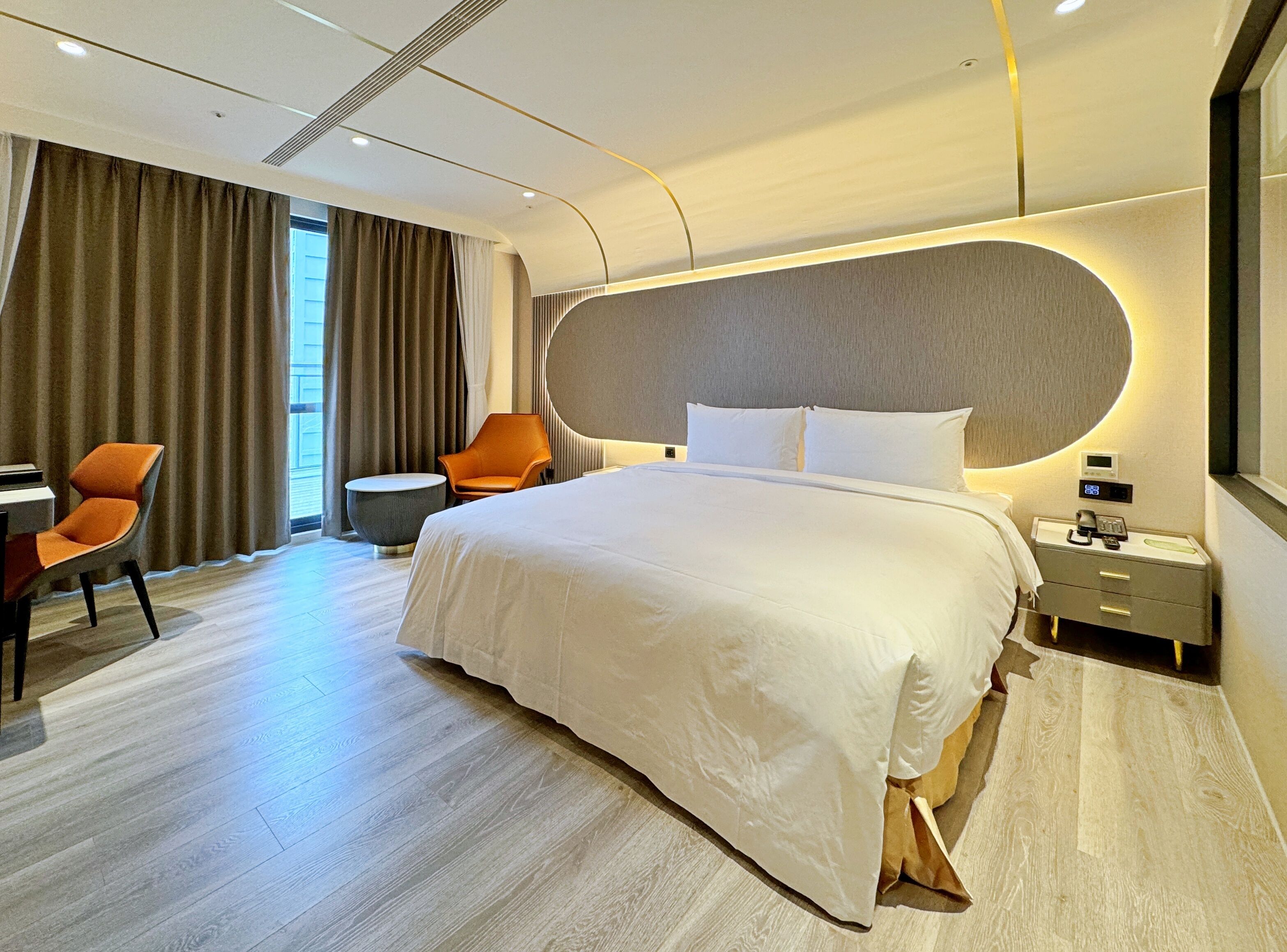 A modern hotel room with a large bed, a desk, and a chair.