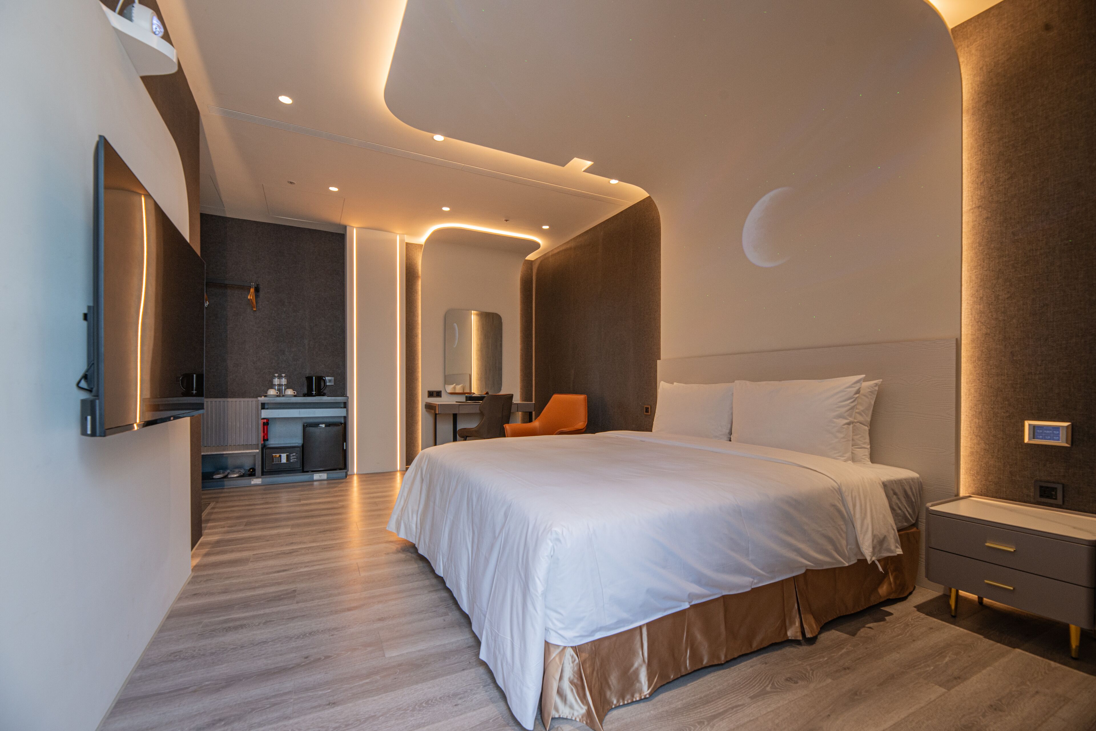 A modern hotel room with a large bed, a desk, and a bathroom.