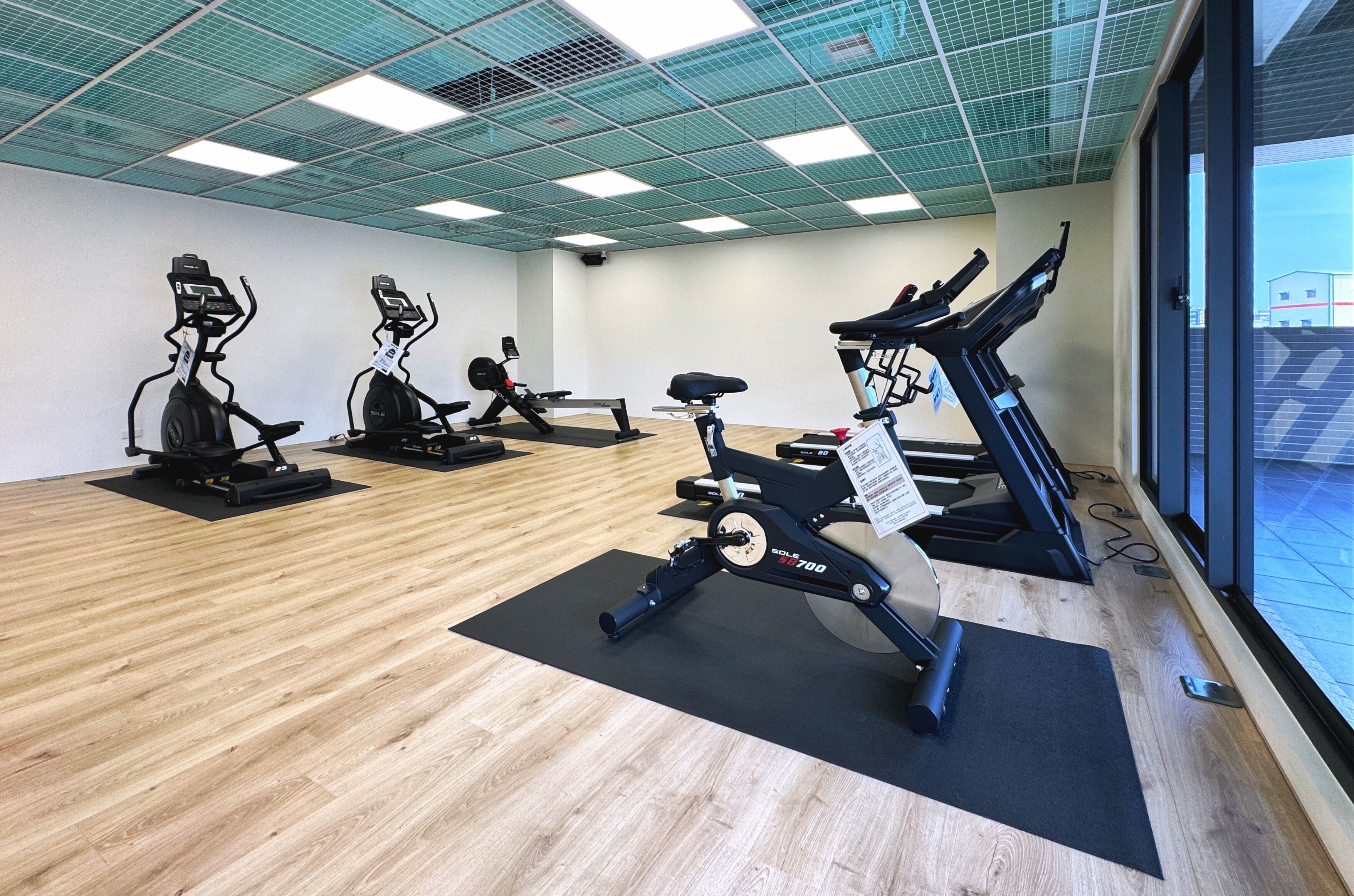 A gym with stationary bikes, a rowing machine, and a bench.