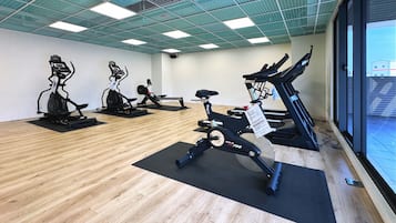 A gym with stationary bikes, a rowing machine, and a bench.