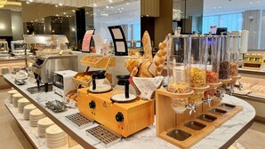 Un buffet de petit-déjeuner proposant une variété d’aliments, des machines à café et un espace de libre-service pour les boissons.