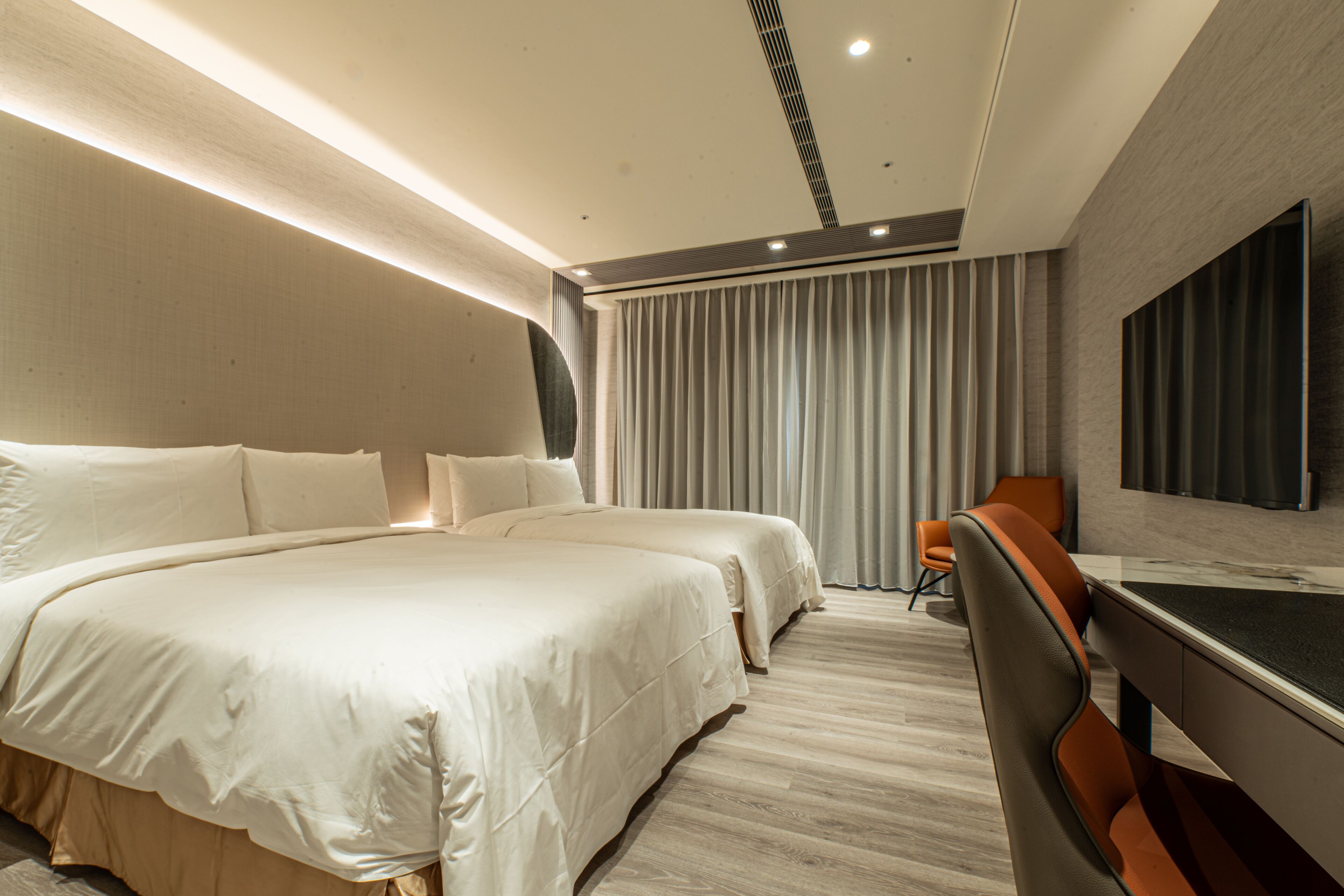 A modern hotel room with a large bed, two bedside tables, a desk, and a chair.