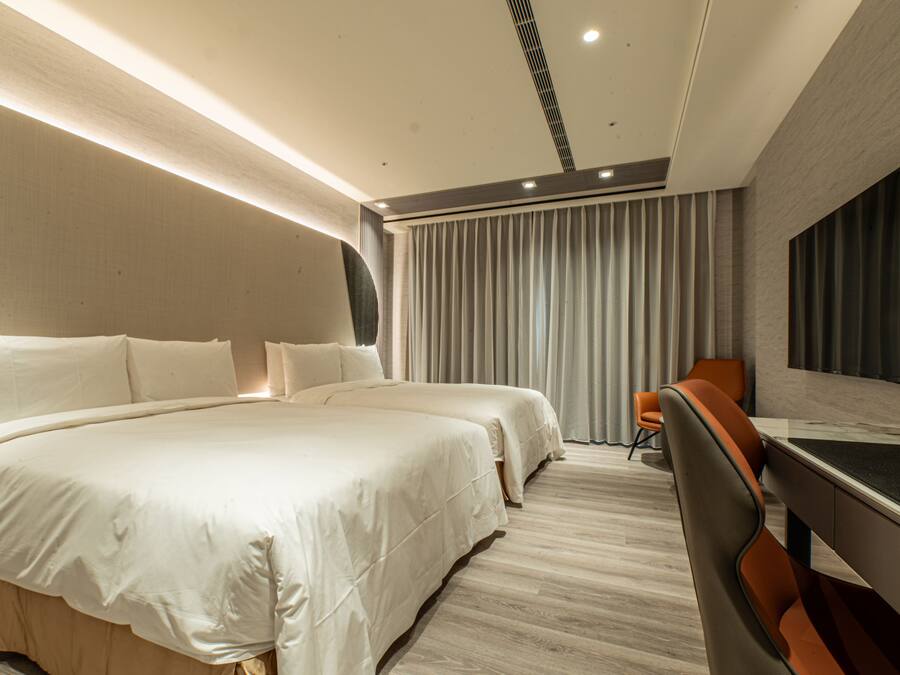 Una habitación de hotel moderna con una cama grande, dos mesitas de noche, un escritorio y una silla.